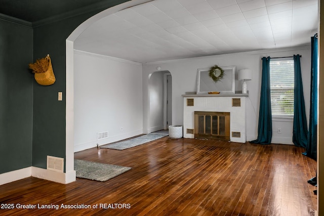 229 Rockingham Ave, Alma, MI 48801 - unfurnished living room featuring arched walkways, hardwood / wood-style flooring, crown molding, and a fireplace