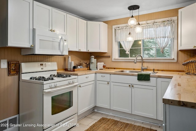 229 Rockingham Ave, Alma, MI 48801 - kitchen featuring white appliances, white cabinets, wooden walls, light tile patterned floors, and light countertops