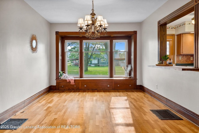 301 E Emerson St, Ithaca, MI 48847 - unfurnished dining area with light wood-type flooring and a chandelier