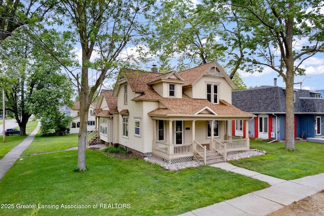 301 E Emerson St, Ithaca, MI 48847 - victorian home with covered porch, roof with shingles, a front yard, and a chimney