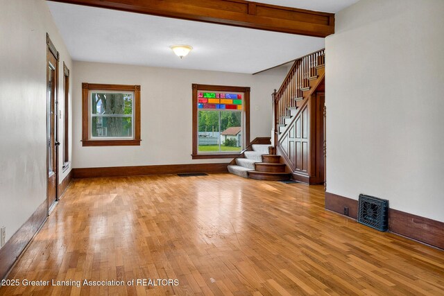 301 E Emerson St, Ithaca, MI 48847 - unfurnished living room with light wood-style flooring, stairs, and beamed ceiling