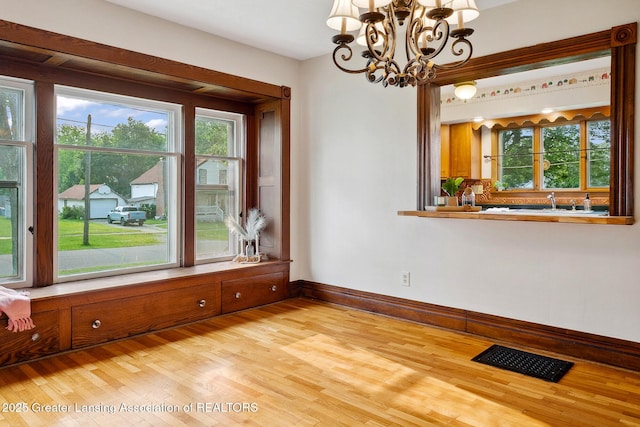 301 E Emerson St, Ithaca, MI 48847 - unfurnished dining area featuring a chandelier, light wood finished floors, and plenty of natural light