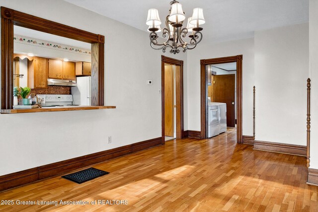 301 E Emerson St, Ithaca, MI 48847 - unfurnished dining area with light wood-type flooring, a chandelier, and washer / dryer
