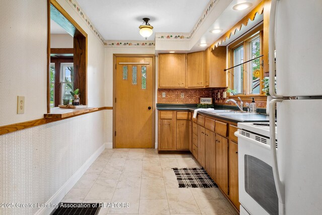 301 E Emerson St, Ithaca, MI 48847 - kitchen with white appliances, healthy amount of natural light, wallpapered walls, dark countertops, and decorative backsplash