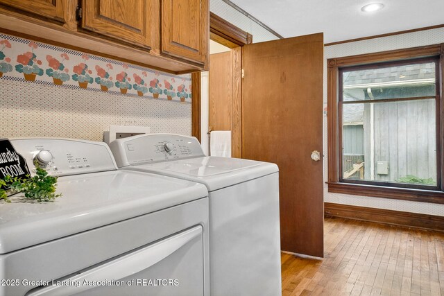301 E Emerson St, Ithaca, MI 48847 - laundry area featuring wallpapered walls, washing machine and dryer, light wood finished floors, cabinet space, and ornamental molding