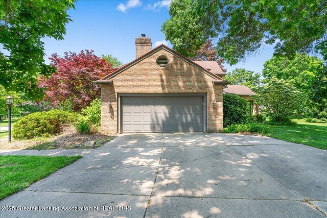 3886 Hemmingway Dr, Okemos, MI 48864 - view of front of home with brick siding, a chimney, driveway, and a garage
