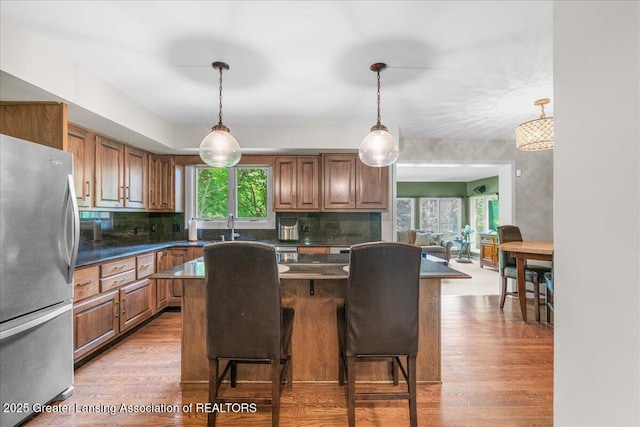3886 Hemmingway Dr, Okemos, MI 48864 - kitchen featuring freestanding refrigerator, dark countertops, light wood-type flooring, and backsplash