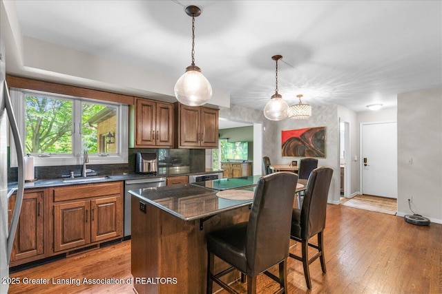3886 Hemmingway Dr, Okemos, MI 48864 - kitchen featuring dishwasher, a kitchen breakfast bar, decorative light fixtures, and light wood-type flooring