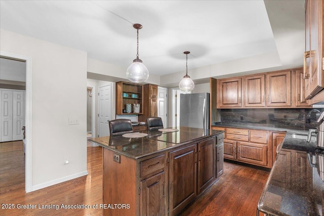 3886 Hemmingway Dr, Okemos, MI 48864 - kitchen featuring freestanding refrigerator, decorative backsplash, dark wood finished floors, and dark stone counters
