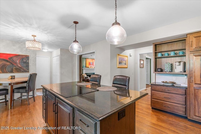 3886 Hemmingway Dr, Okemos, MI 48864 - kitchen with light wood finished floors, a center island, decorative light fixtures, black electric cooktop, and open shelves