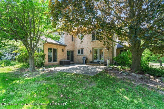 3886 Hemmingway Dr, Okemos, MI 48864 - back of property featuring french doors, brick siding, a patio area, and a lawn