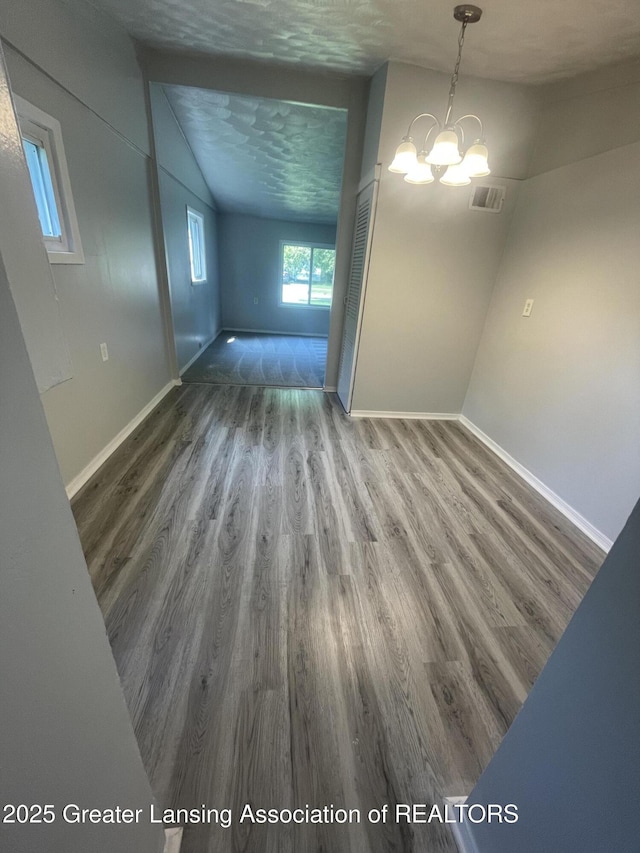 4013 Ingham St, Lansing, MI 48911 - unfurnished dining area with wood finished floors, a chandelier, and lofted ceiling