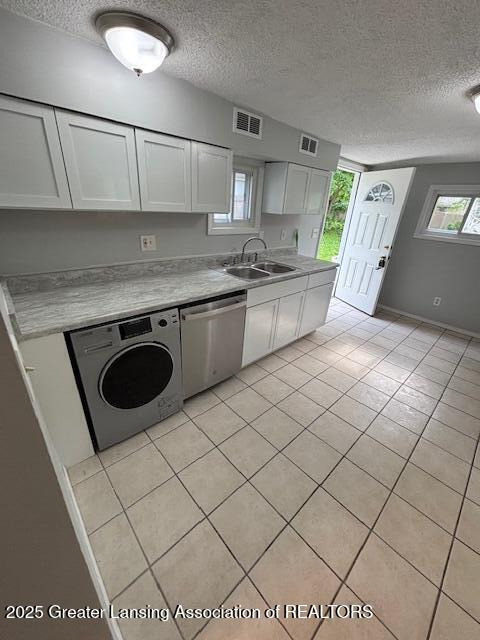 4013 Ingham St, Lansing, MI 48911 - kitchen featuring stainless steel dishwasher, washer / dryer, a textured ceiling, white cabinetry, and light tile patterned flooring