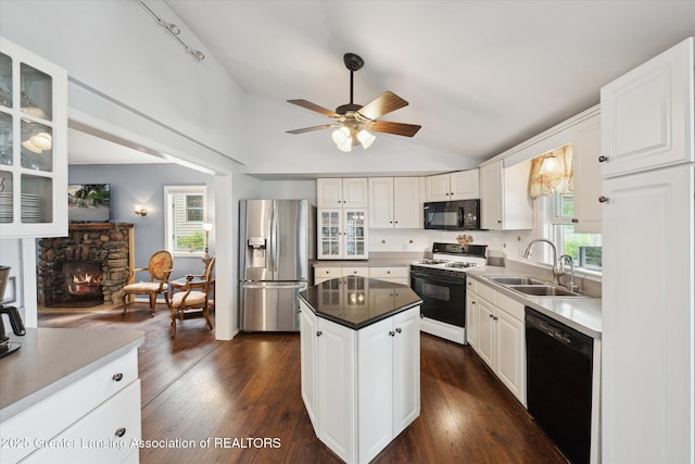 15754 Culver Dr, East Lansing, MI 48823 - kitchen with black appliances, lofted ceiling, ceiling fan, glass insert cabinets, and a center island