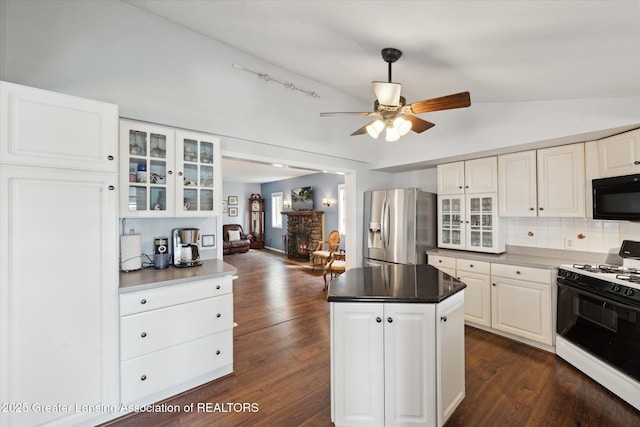 15754 Culver Dr, East Lansing, MI 48823 - kitchen featuring white gas range oven, stainless steel fridge with ice dispenser, black microwave, vaulted ceiling, and glass insert cabinets