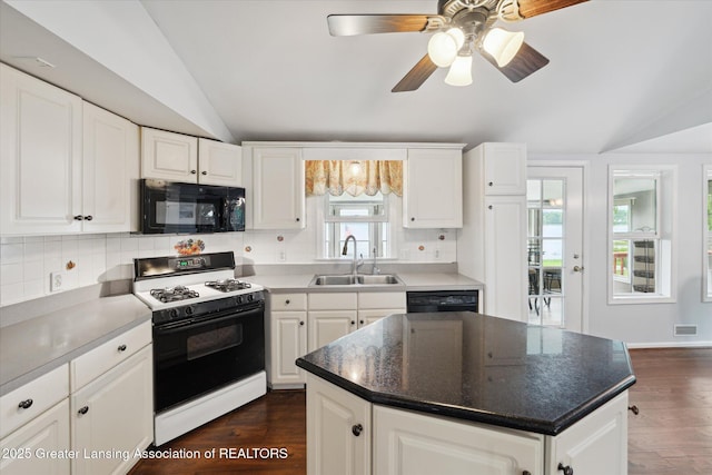15754 Culver Dr, East Lansing, MI 48823 - kitchen featuring black microwave, range with gas stovetop, lofted ceiling, dark wood-type flooring, and decorative backsplash