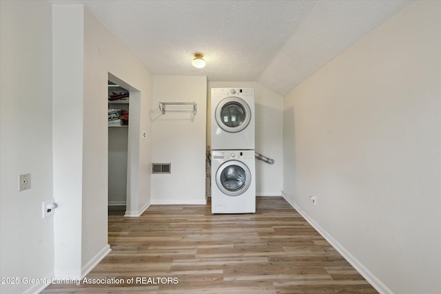 15754 Culver Dr, East Lansing, MI 48823 - laundry room with stacked washer / drying machine, light wood-style flooring, and a textured ceiling
