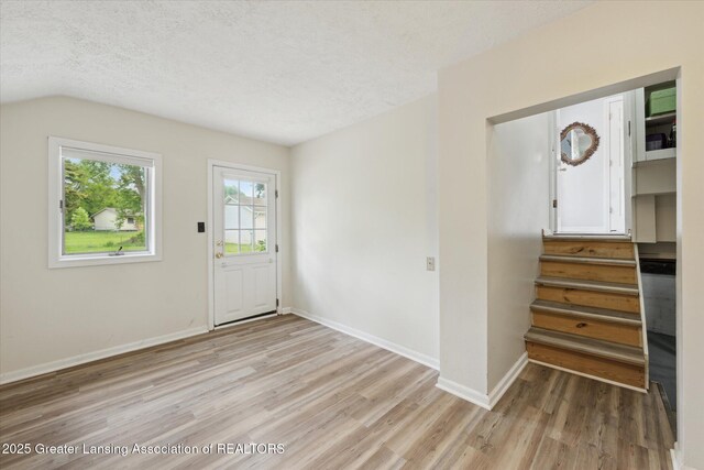 15754 Culver Dr, East Lansing, MI 48823 - entryway with light wood-type flooring, a textured ceiling, stairway, and vaulted ceiling