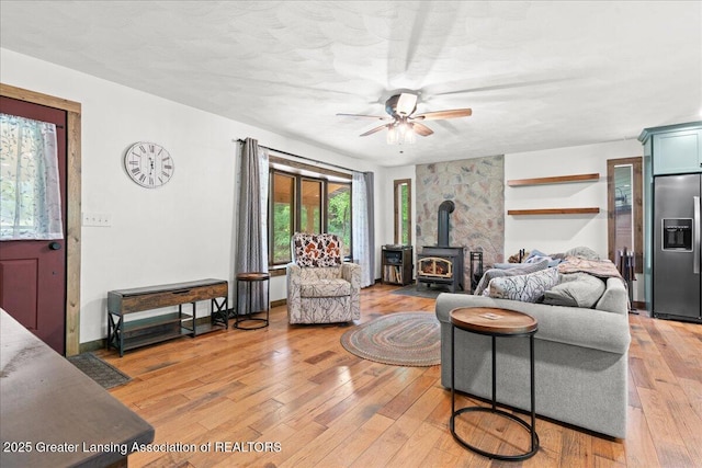 11100 S Bird Rd, Dowling, MI 49050 - living room with a wood stove, a ceiling fan, and light wood-style floors