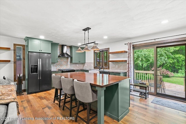 11100 S Bird Rd, Dowling, MI 49050 - kitchen featuring green cabinets, stainless steel refrigerator with ice dispenser, wall chimney range hood, butcher block countertops, and tasteful backsplash