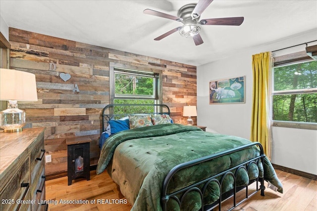 11100 S Bird Rd, Dowling, MI 49050 - bedroom with multiple windows, wooden walls, and light wood-style floors
