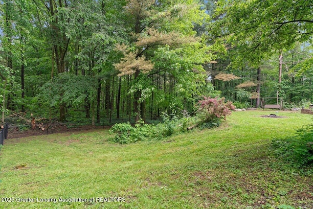 11100 S Bird Rd, Dowling, MI 49050 - view of green lawn featuring an outdoor fire pit and a forest view