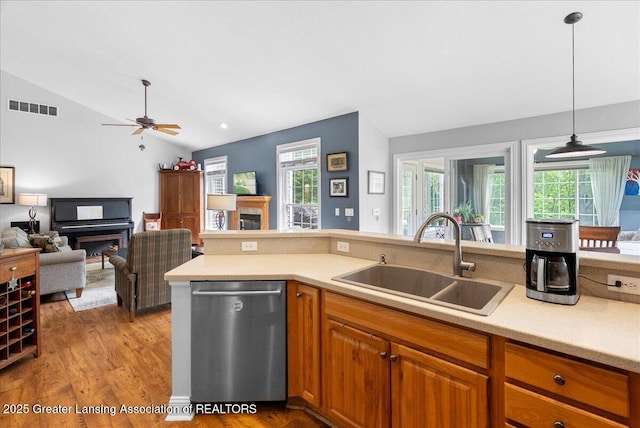 2308 Keller Rd, Holt, MI 48842 - kitchen featuring stainless steel dishwasher, a fireplace, vaulted ceiling, light countertops, and light wood finished floors