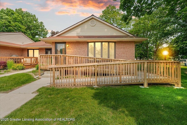 235 Bonnie Brook Dr Unit 1, Charlotte, MI 48813 - view of front of home featuring a deck, brick siding, and a yard