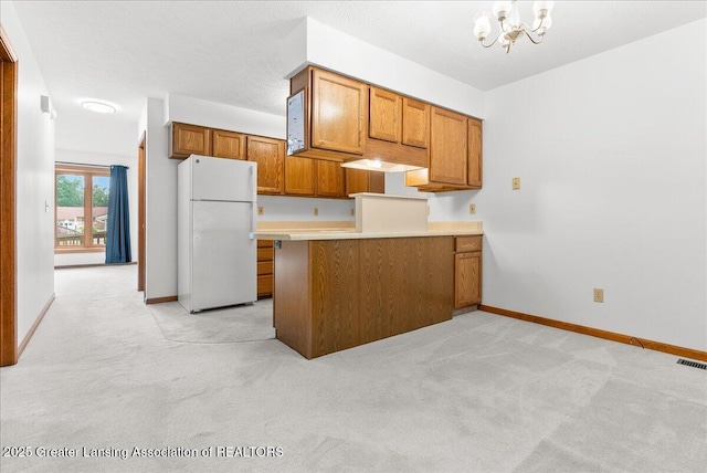 235 Bonnie Brook Dr Unit 1, Charlotte, MI 48813 - kitchen with freestanding refrigerator, brown cabinetry, light colored carpet, and a chandelier