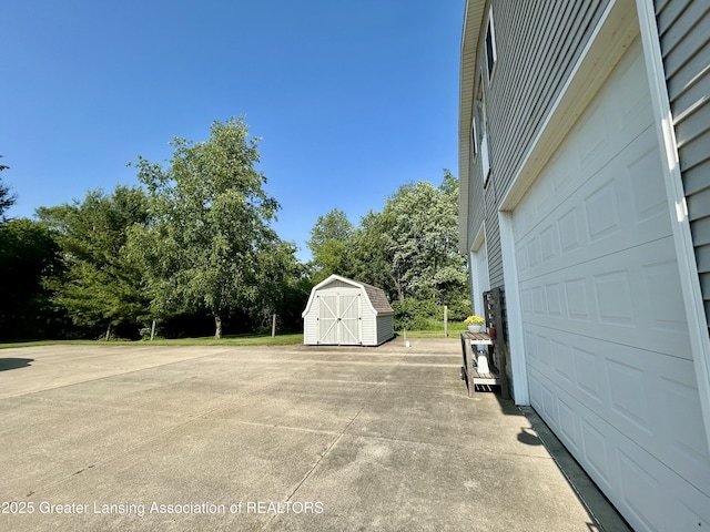 10497 Charlotte Hwy, Portland, MI 48875 - view of patio / terrace featuring a garage, a storage shed, and view of wooded area