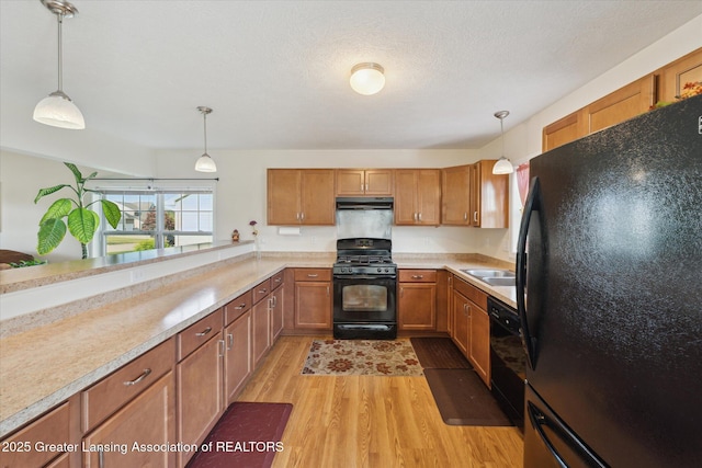 8687 Yellowstone Ln, Lansing, MI 48917 - kitchen featuring black appliances, under cabinet range hood, brown cabinets, light wood finished floors, and light countertops