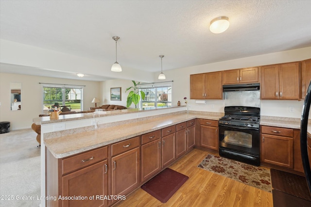8687 Yellowstone Ln, Lansing, MI 48917 - kitchen featuring black range with gas cooktop, under cabinet range hood, a peninsula, open floor plan, and light countertops