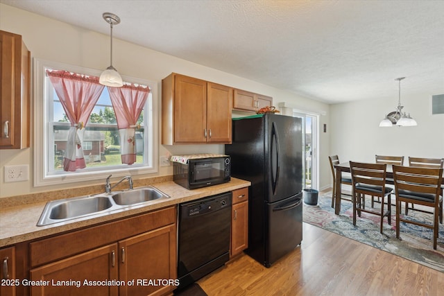 8687 Yellowstone Ln, Lansing, MI 48917 - kitchen featuring black appliances, light wood-style flooring, plenty of natural light, brown cabinetry, and a textured ceiling