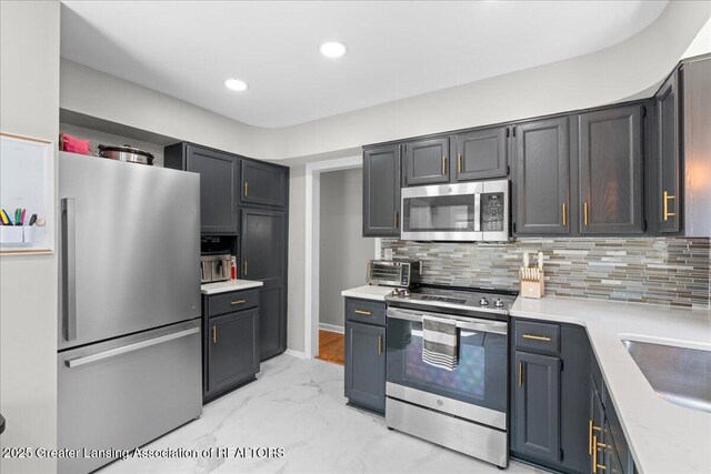 952 Sunset Ln, East Lansing, MI 48823 - kitchen featuring stainless steel appliances, light marble finish floors, light countertops, decorative backsplash, and recessed lighting