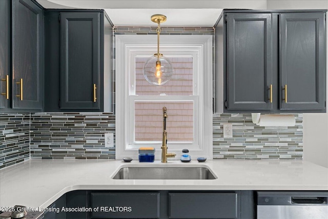 952 Sunset Ln, East Lansing, MI 48823 - kitchen featuring stainless steel dishwasher, decorative backsplash, light countertops, and hanging light fixtures