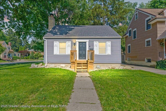 952 Sunset Ln, East Lansing, MI 48823 - view of front of home with a chimney, a front yard, and a shingled roof