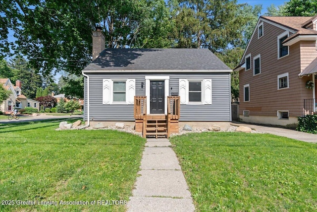 952 Sunset Ln, East Lansing, MI 48823 - view of front facade featuring a front yard, a chimney, and a shingled roof