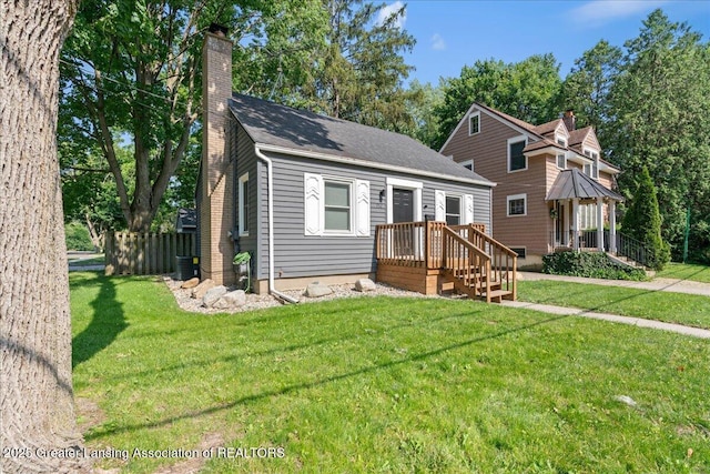 952 Sunset Ln, East Lansing, MI 48823 - view of front of house featuring a chimney, a front yard, and a shingled roof