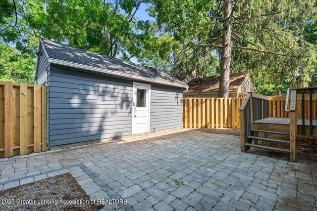 952 Sunset Ln, East Lansing, MI 48823 - fenced backyard featuring a patio area, an outbuilding, and a wooden deck