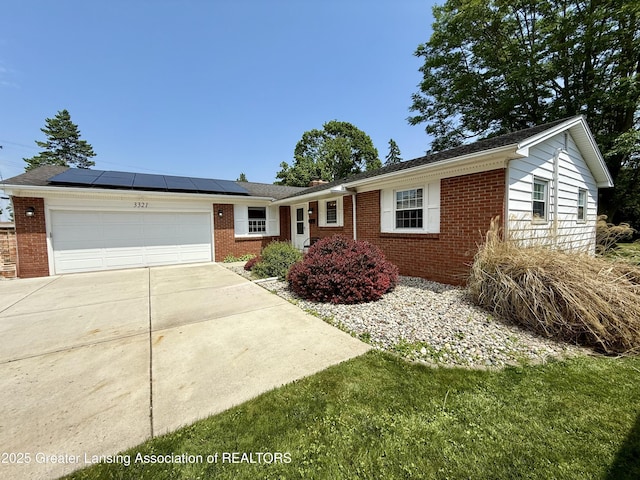 3321 Springbrook Ln, Lansing, MI 48917 - single story home featuring brick siding, an attached garage, roof mounted solar panels, and concrete driveway