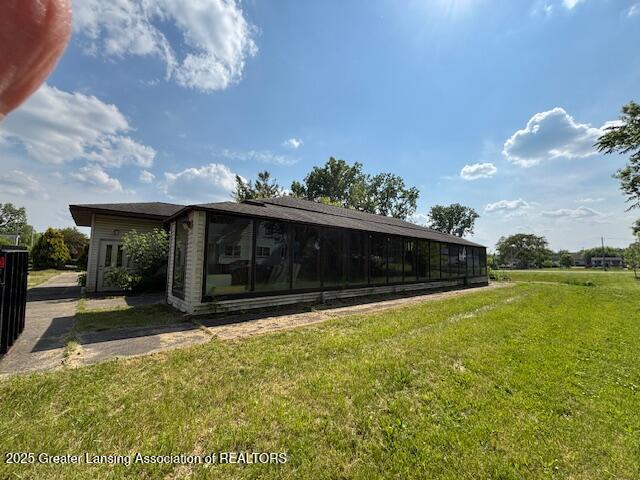 5681 Shaw St, Haslett, MI 48840 - back of property with a lawn and a sunroom