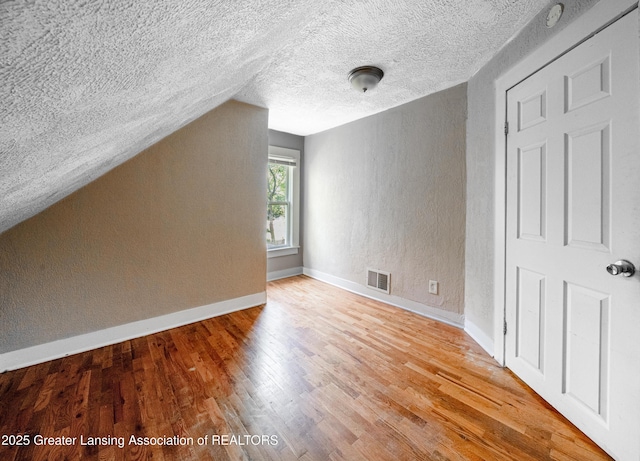 1407 W Ionia St, Lansing, MI 48915 - additional living space with a textured ceiling, wood finished floors, a textured wall, and vaulted ceiling
