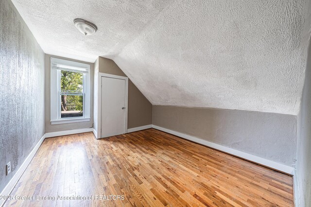 1407 W Ionia St, Lansing, MI 48915 - bonus room featuring a textured ceiling, hardwood / wood-style flooring, vaulted ceiling, and a textured wall