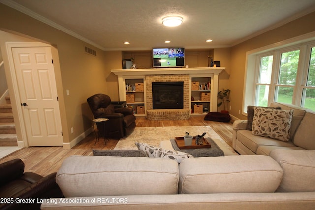 8522 Ember Glen Pass, Lansing, MI 48917 - living room featuring wood finished floors, ornamental molding, recessed lighting, a brick fireplace, and stairs
