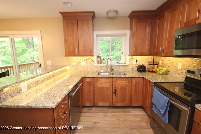 8522 Ember Glen Pass, Lansing, MI 48917 - kitchen featuring appliances with stainless steel finishes, a peninsula, light wood-style floors, and brown cabinetry