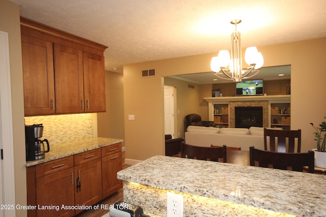 8522 Ember Glen Pass, Lansing, MI 48917 - kitchen with a chandelier, dark wood-style floors, tasteful backsplash, brown cabinets, and hanging light fixtures