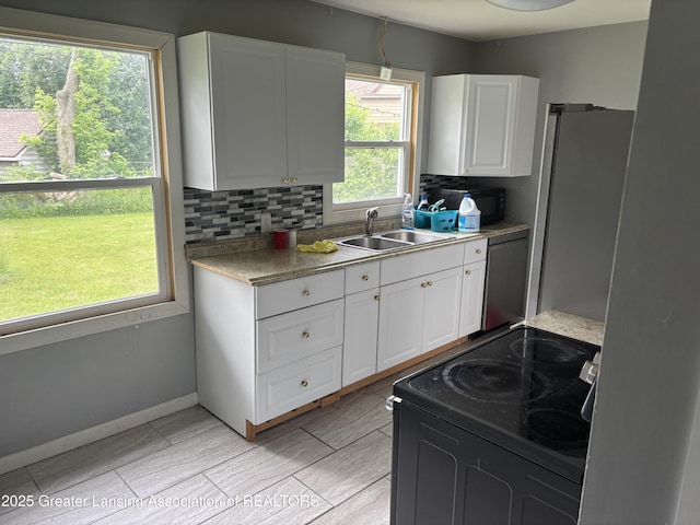 1311 W Saginaw St, East Lansing, MI 48823 - kitchen featuring appliances with stainless steel finishes, white cabinets, decorative backsplash, and light countertops