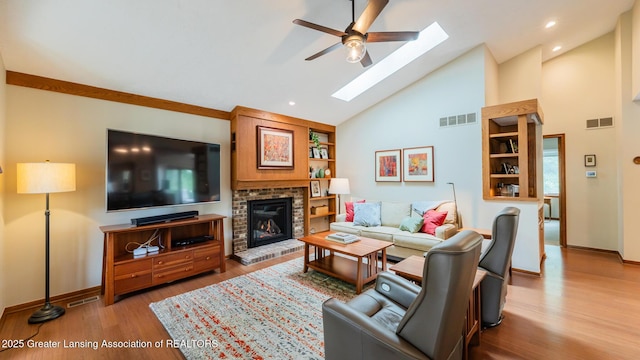 3522 Apple Valley Rd, Okemos, MI 48864 - living area featuring a skylight, ceiling fan, wood finished floors, high vaulted ceiling, and a fireplace