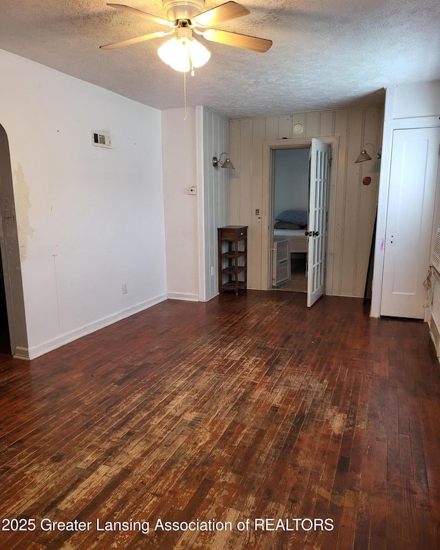 1517 Hyland St, Lansing, MI 48915 - unfurnished living room featuring dark wood-style floors, a textured ceiling, a ceiling fan, and arched walkways