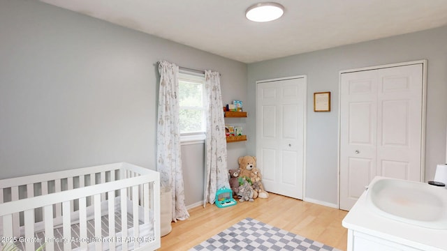 6916 Toboggan Ln, Lansing, MI 48917 - bedroom with light wood-type flooring, two closets, and a crib